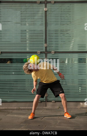 Manchester UK. European Freestyle Soccer Champion John Farnworth, MR, showing his football 'Keepy Uppy' skills, tricks, fun, lifestyle, fitness, happy, practice, recreation, talented , exercise, game, kicking football, a Pelé-inspired freestyle performance, in the streets near the Urbis National Football Museum.  World Cup 100 Day Countdown Carnival a day of celebrations as Mardi Gras to celebrate the beginning of the 100 day countdown to this year’s World Cup!  John is a football freestyler and entertainer who holds four Guinness World Records including the most around the worlds in a minute. Stock Photo