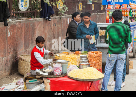 Local Indian street seller on pavement with attractive food in New Delhi, India, ladling a bowl of street food for a customer Stock Photo
