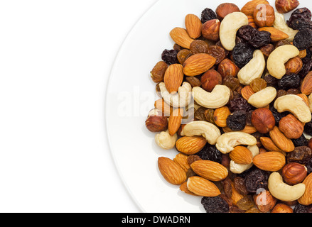 Mixed nuts and dry fruits in plate isolated on white background close-up Stock Photo
