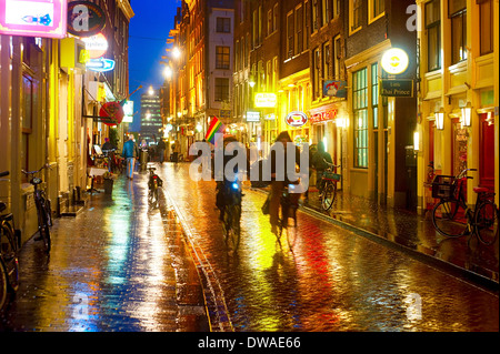 Unidentified people on the street of an old town of Amsterdam in the evening under the rain. Stock Photo