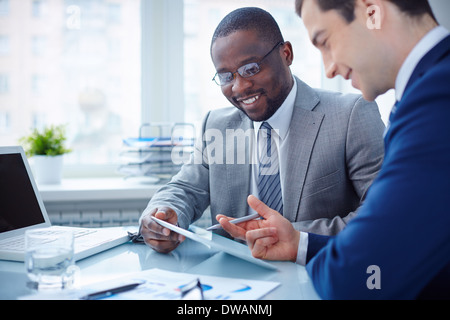 Image of two young businessmen interacting at meeting in office Stock Photo