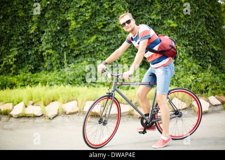 Portrait of handsome guy sitting on bicycle in the park Stock Photo