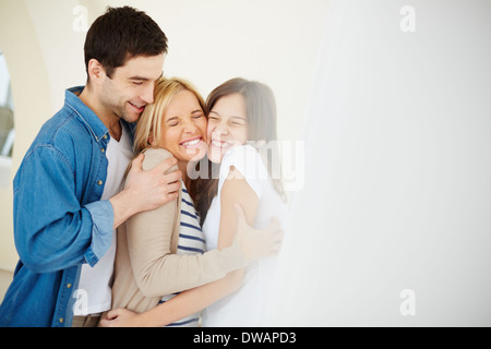 Portrait of joyful family of three in embrace Stock Photo