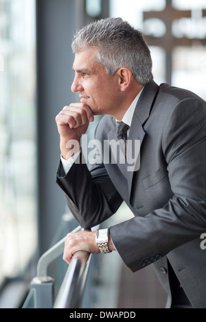 thoughtful senior businessman looking out the window Stock Photo