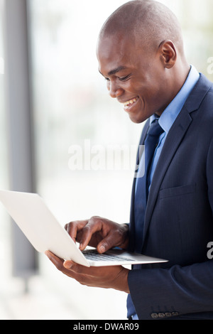 smiling young African American businessman using laptop computer indoors Stock Photo