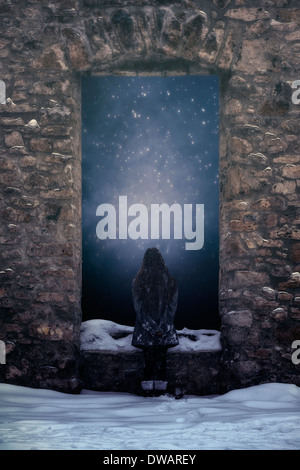 a girl is standing in front of a window of an old castle in the snow Stock Photo