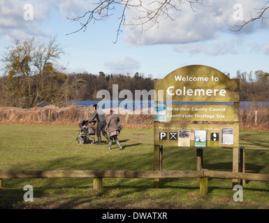 Family walking with a pram or pushchair past the sign at Colemere Country heritage site Shropshire England UK Stock Photo