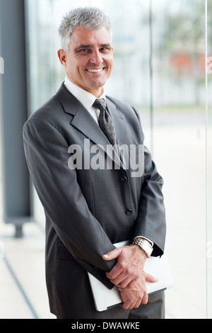 smiling mature businessman standing in modern office Stock Photo
