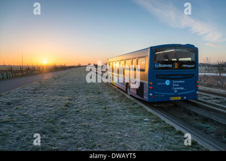 Longstanton, Cambridgeshire, UK. 5th March 2014. A guided bus travels at sunrise on the guided busway towards Cambridge UK on a frosty and sunny morning 5th March 2014.  A sunny day is expected across the East of England today with a warm spell forecast later in the week.  The guided busway runs from Cambridge to St Ives in Cambridgeshire and is the longest in the world with buses running on a purpose built concrete track.  Credit Julian Eales/Alamy Live News Stock Photo