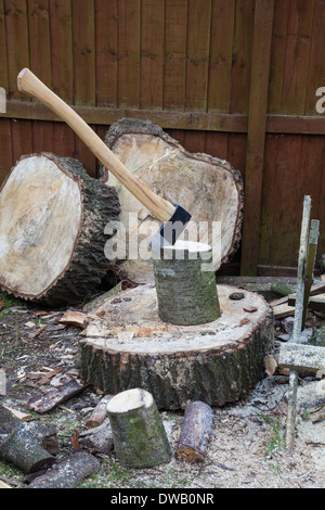 An axe in a piece of wood on a chopping block for making firewood, England, UK Stock Photo