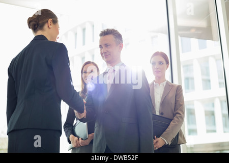 Confident business partners shaking hands in office Stock Photo