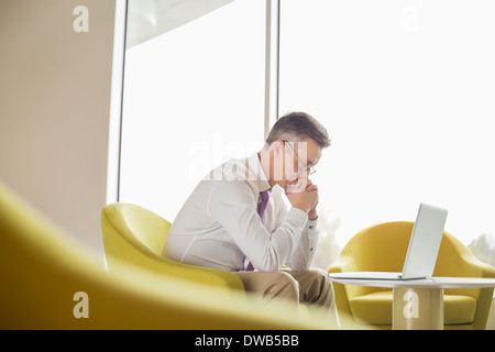 Side view of serious businessman looking at laptop in lobby