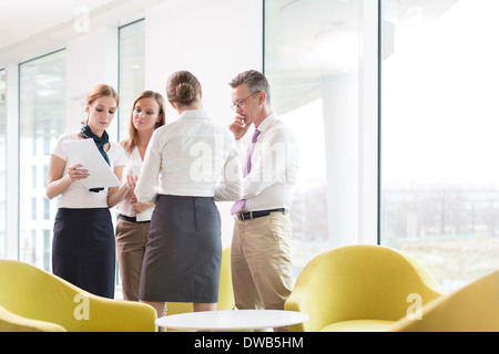 Business people discussing over documents in office lobby Stock Photo