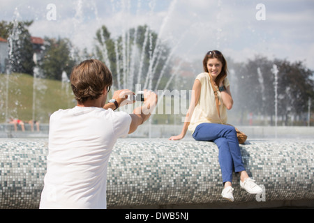 Rear view of man videotaping woman against fountain Stock Photo