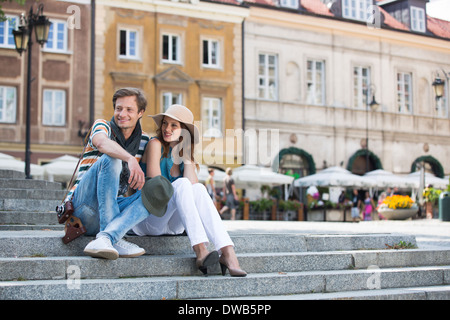 Tourist couple sitting on steps against building Stock Photo