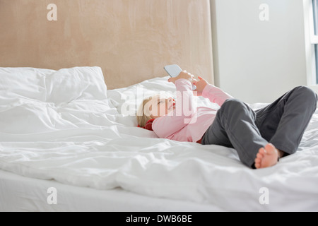 Full length of happy girl using smart phone in bed Stock Photo