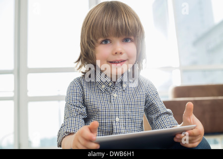 Portrait of cute boy holding tablet computer at home Stock Photo