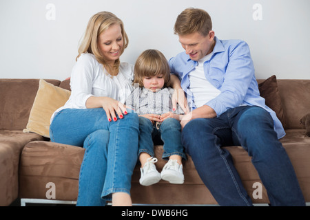 Parents sitting with sad son on sofa at home Stock Photo