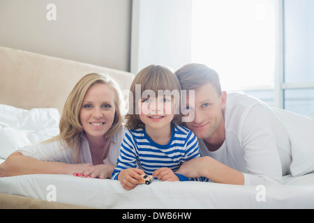 Portrait of happy parents lying with son in bed Stock Photo