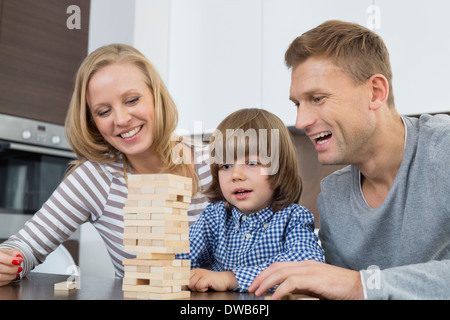 Happy parents and son playing with wooden blocks at home