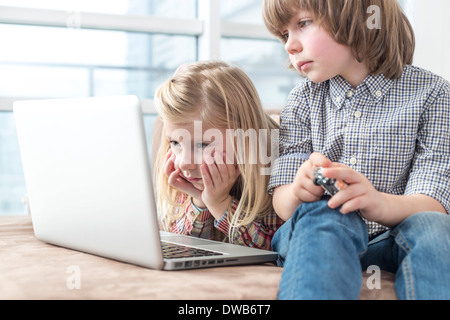 Brother and sister looking at laptop in living room Stock Photo