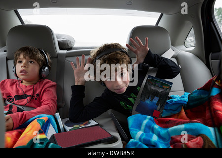 Brothers in back seat of car, wearing headphones Stock Photo