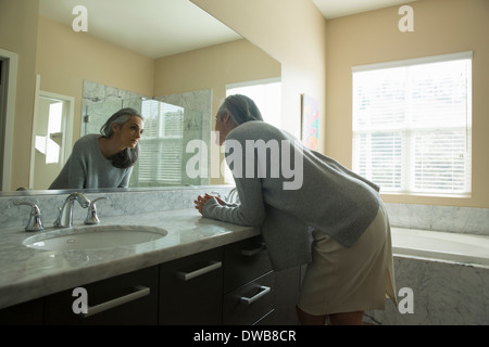 Woman pondering in front of mirror Stock Photo