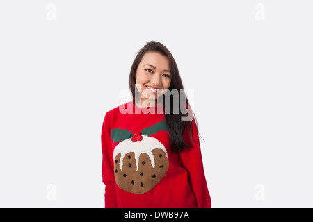 Portrait of happy woman in Christmas sweater standing against gray background Stock Photo