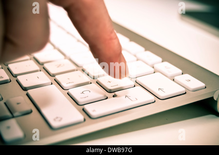 A finger on a white keyboard, ready to press the enter key. Stock Photo