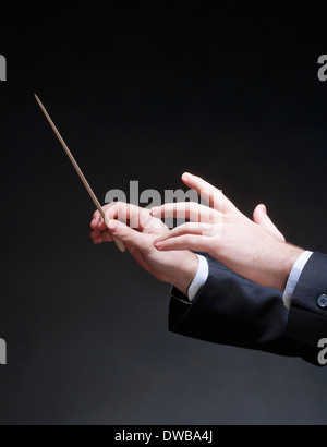 Hands of Conductor with Baton Leading Orchestra Stock Photo