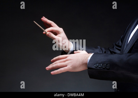 Hands of Conductor with Baton Leading Orchestra Stock Photo