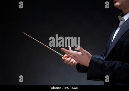 Hands of Conductor with Baton Leading Orchestra Stock Photo