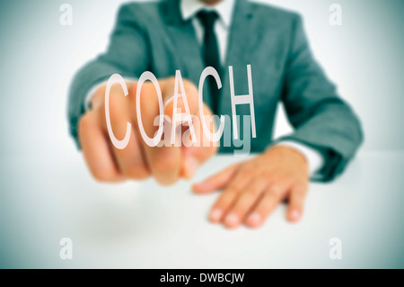 man sitting in a desk pointing the word coach written in the foreground Stock Photo