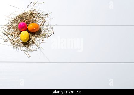 Three coloured Easter eggs and straw on white ground Stock Photo