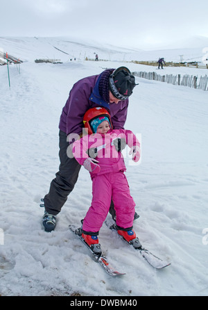 Happy little girl on skis for the first time at Cairngorm Mountain Ski Centre, near Aviemore, Scottish Highlands, Scotland UK Stock Photo