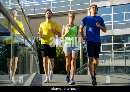 Small group of adult runners on city footbridge Stock Photo