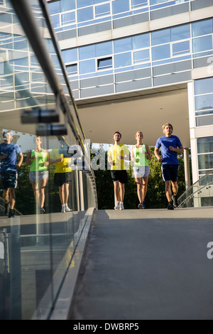 Small group of adult runners crossing city footbridge Stock Photo