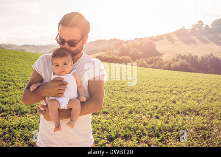 Portrait of proud father holding up baby daughter Stock Photo