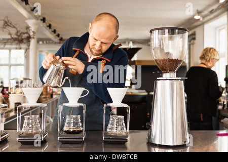 Barista pouring boiling water into coffee filters Stock Photo