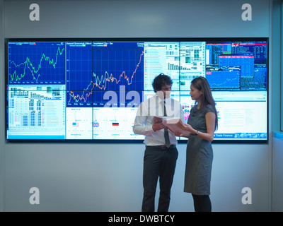 Business people meeting in front of graphical screens Business people meeting in front of graphical screens