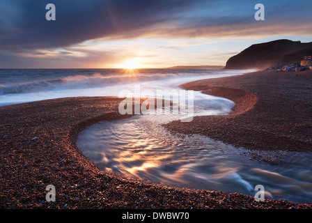 River Winniford flowing into the sea at Seatown Beach with the cliffs of Golden Cap in the Distance. Jurassic Coast. Dorset. UK. Stock Photo