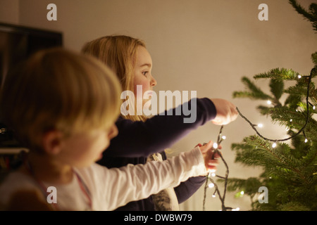 Young brother and sister putting up christmas lights Stock Photo