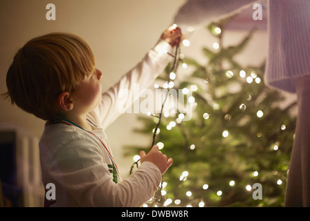 Young boy putting up christmas tree lights