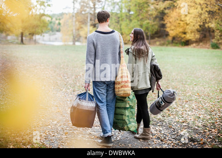 Rear view of couple carrying luggage while camping in forest Stock Photo