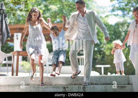 Parents lifting son over steps Stock Photo