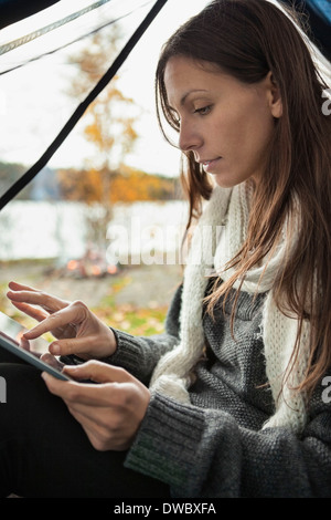 Young woman using digital tablet in tent Stock Photo