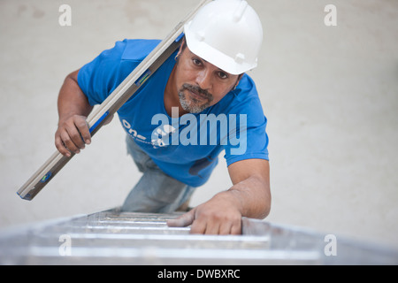 Builder with metal rod climbing ladder Stock Photo