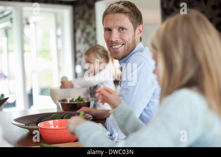 Portrait of smiling man cooking food with daughters in kitchen Stock Photo