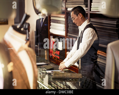 Tailor working at counter in tailors shop Stock Photo