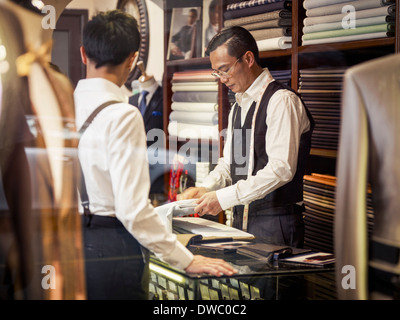Father and son looking at fabric in family tailors shop Stock Photo